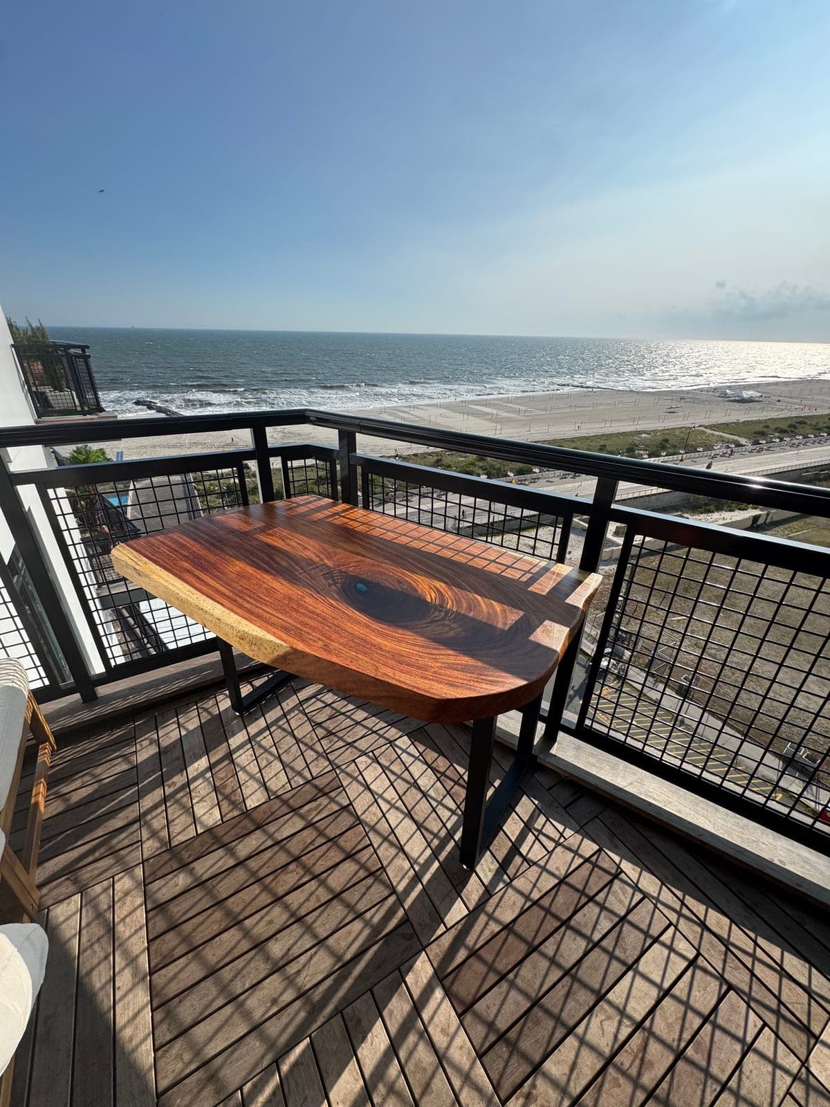 Live-edge table with a dark resin center on an ocean-view balcony