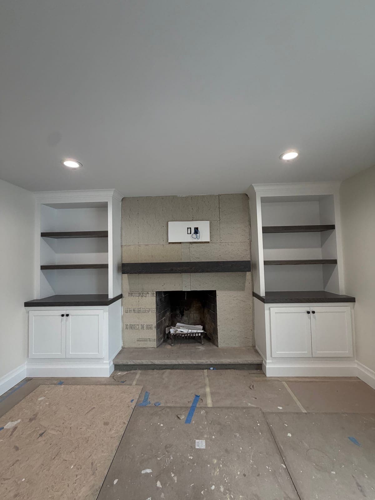 White built-in cabinets and shelves on both sides of a fireplace