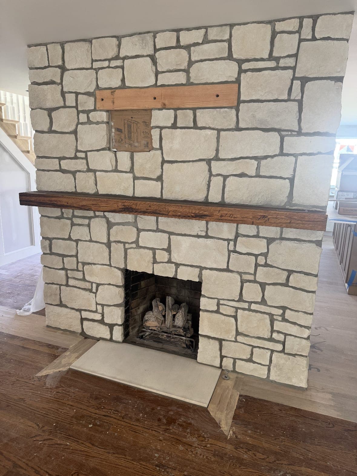 Stacked-stone fireplace with a stained wood beam mantel
