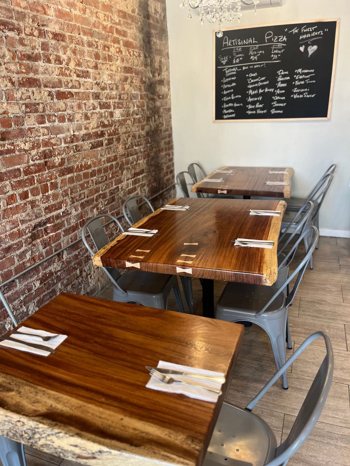 Dark wood restaurant tables with bowtie inlays against a brick wall