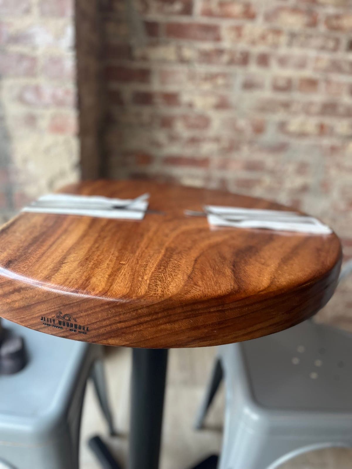 Round wood tabletop with the Jetty Woodwork brand burned into its edge