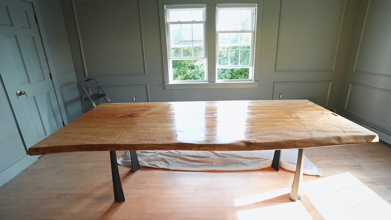 Live-edge slab dining table on black steel legs in a dining room with paneled walls